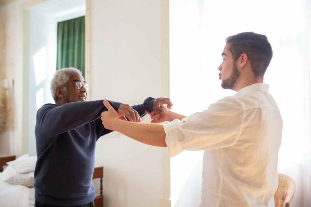 man helping elder to exercise